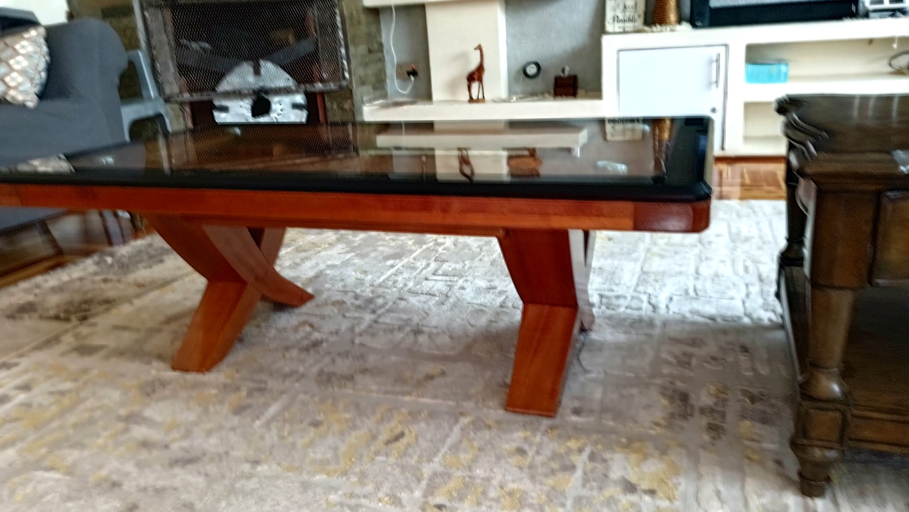 Wooden X-frame coffee table with glass top in a living room